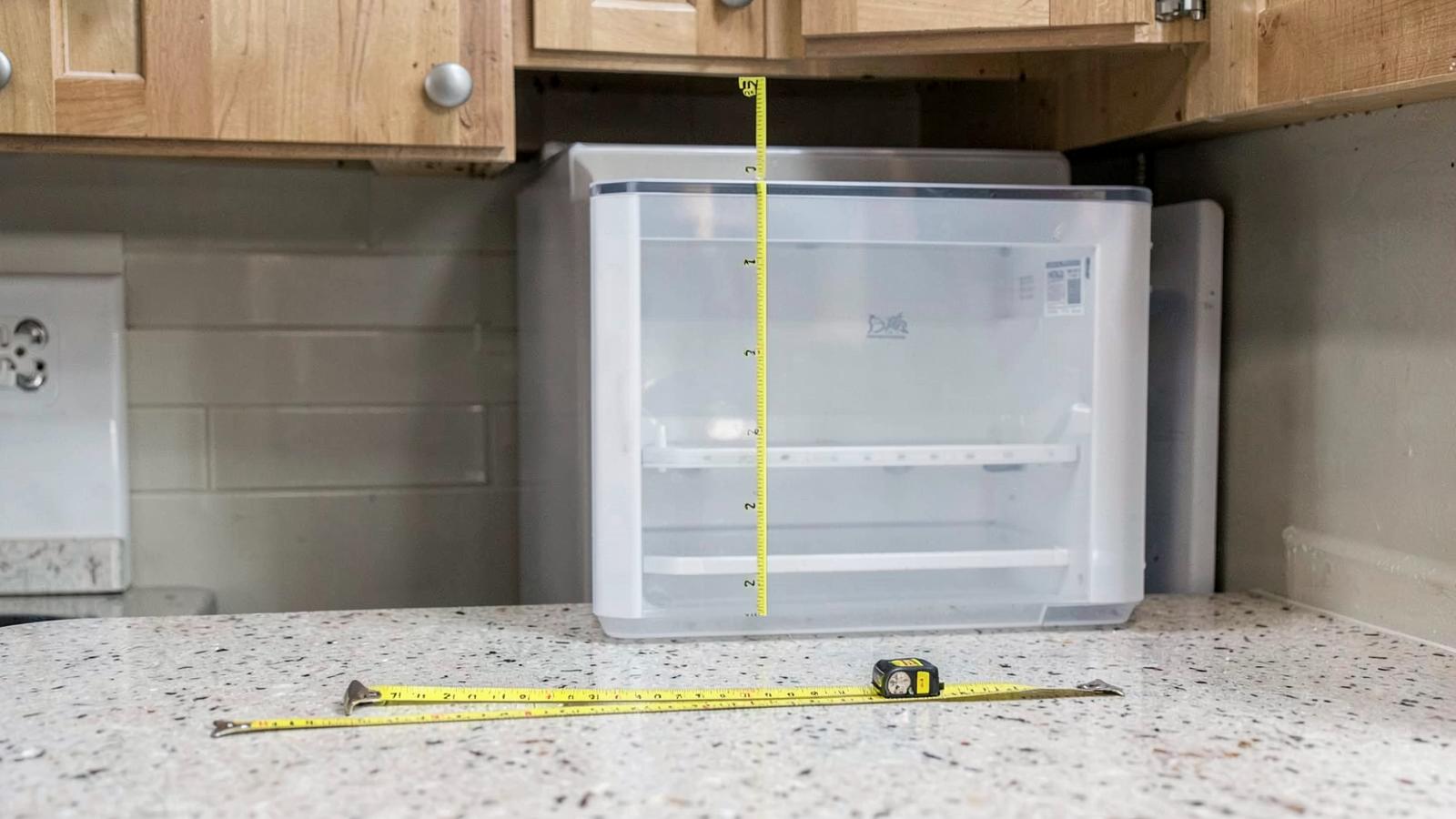 Tape measure checking the clearance above a countertop ice maker