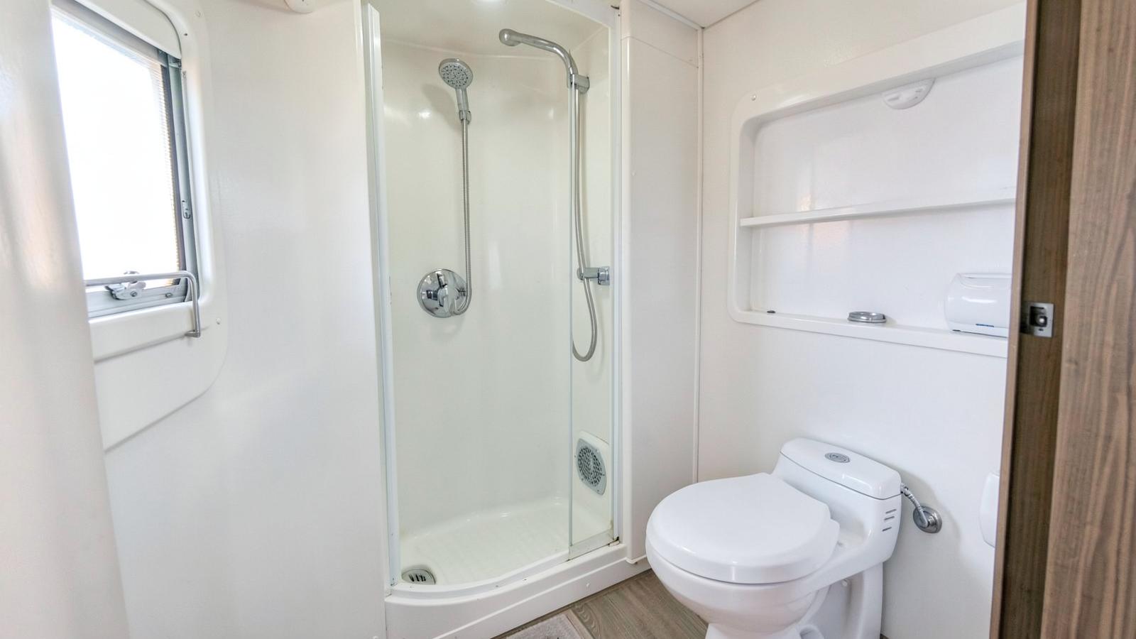 Compact RV bathroom with a shower stall, handheld shower head and toilet