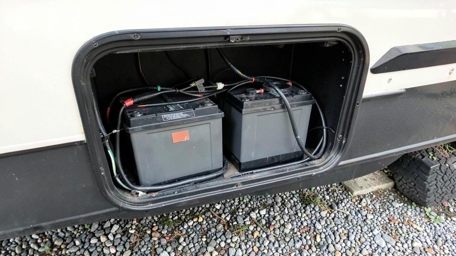 Open exterior battery compartment of a travel trailer with two deep cycle batteries