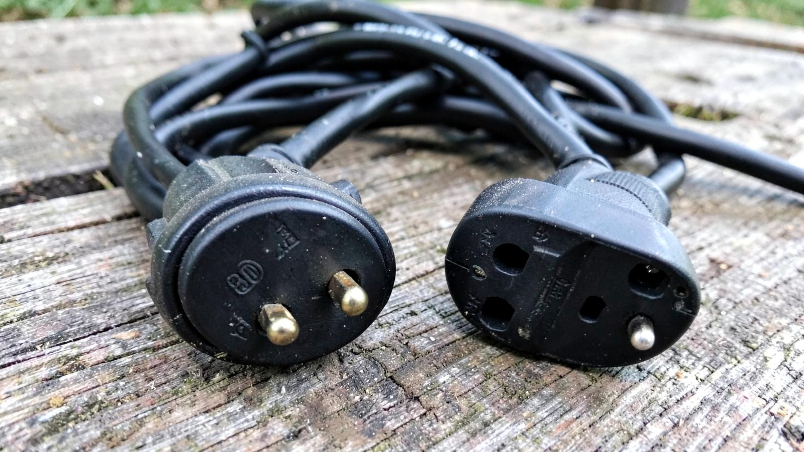 Two heavy RV shore power cords with different plugs on a picnic table