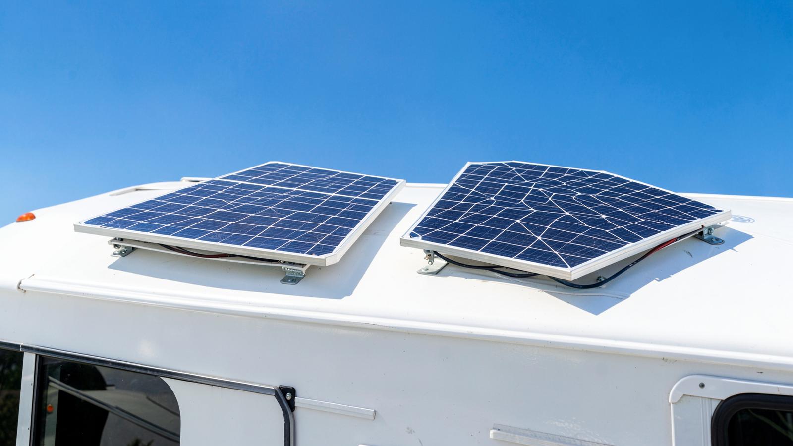 Two solar panels newly mounted on a white RV roof under a clear blue sky