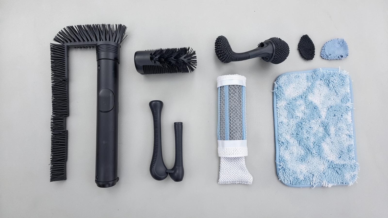 Replacement brushes, filters and mop pads arranged on a grey surface